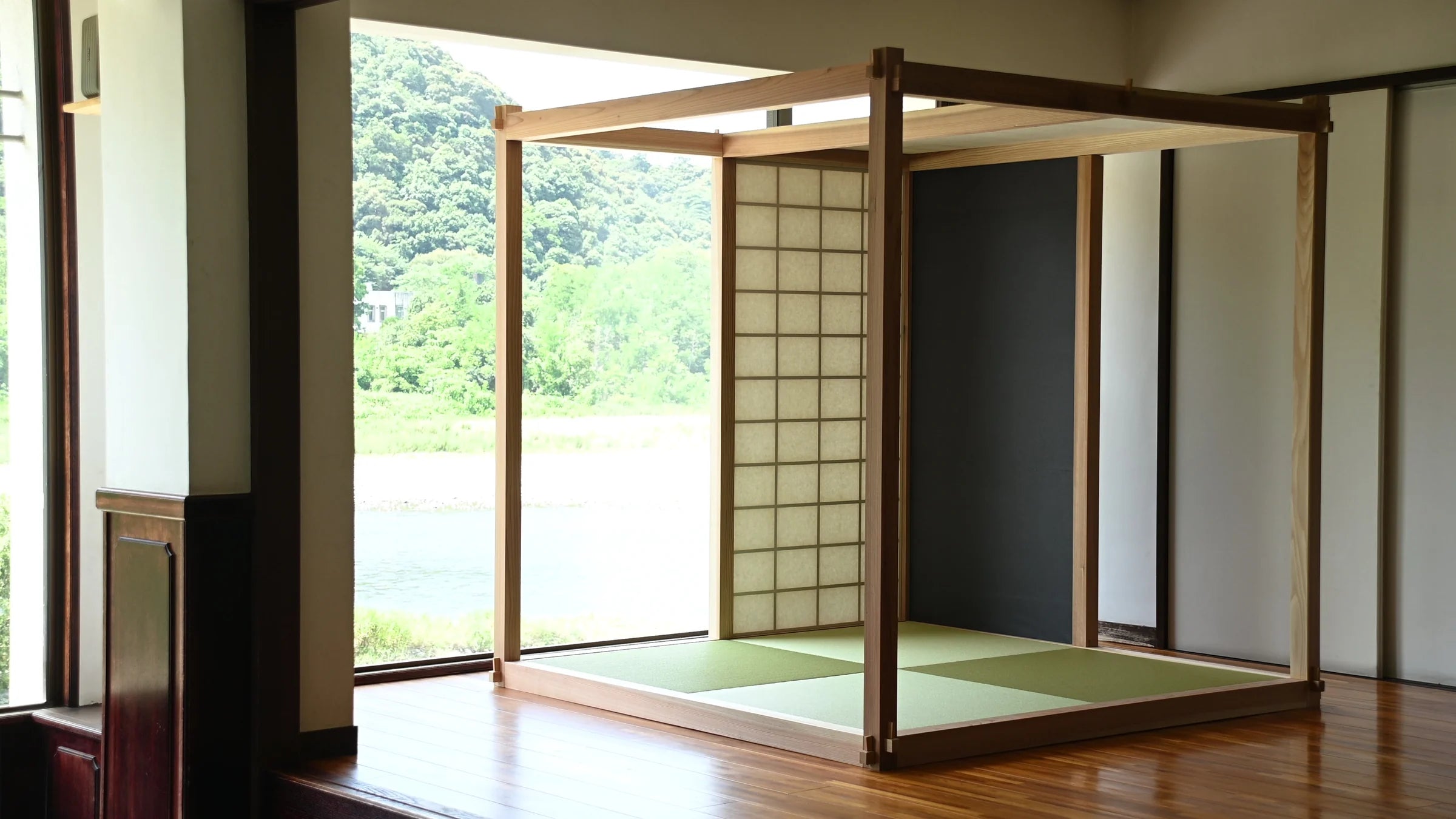 既存の室内に設置された、畳床と紙のパネルを備えた開放的な木組みのZENLAB ROOM。窓の向こうに川が見える。