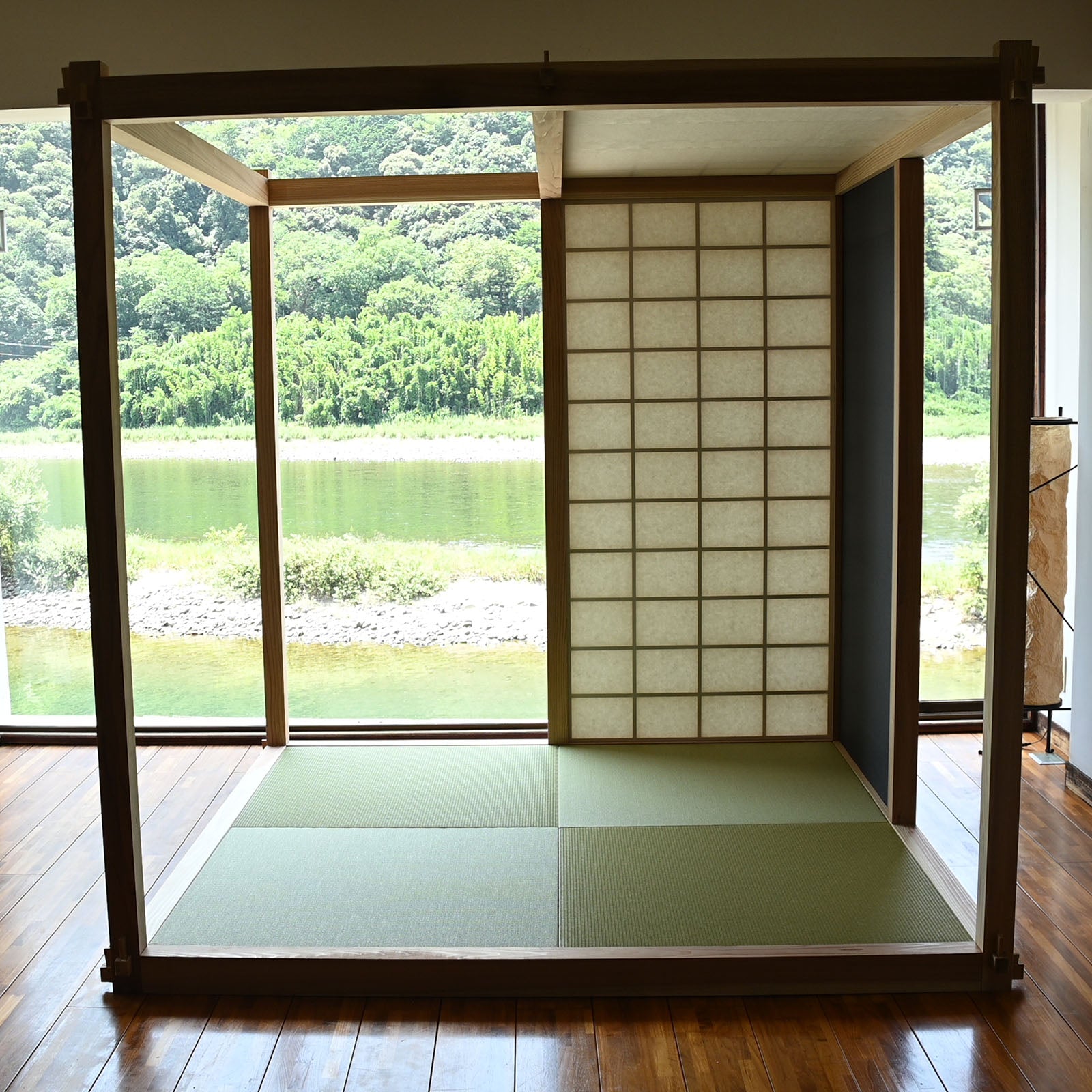 既存の室内に置かれた、木のフレーム、畳、紙張りのパネルがあるRoomの正面。